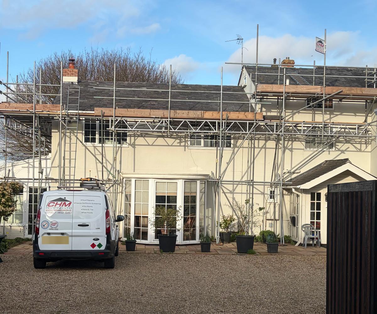 CHM Roofing van on site at a scaffolded cream house during a re-roof