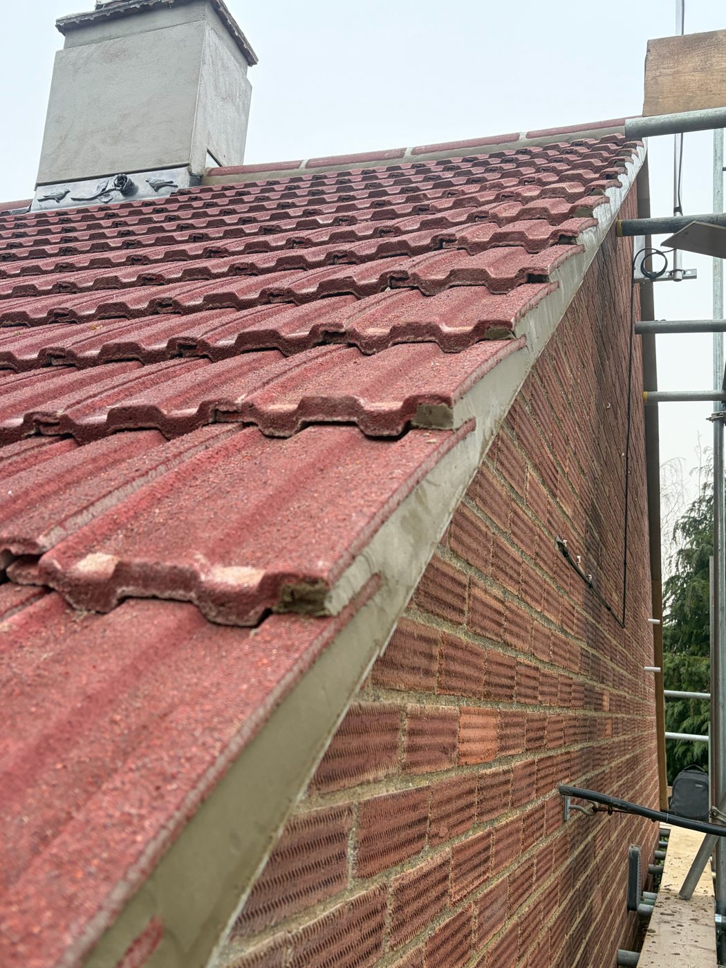 New red interlocking roof tiles with a neat mortar verge on a brick gable
